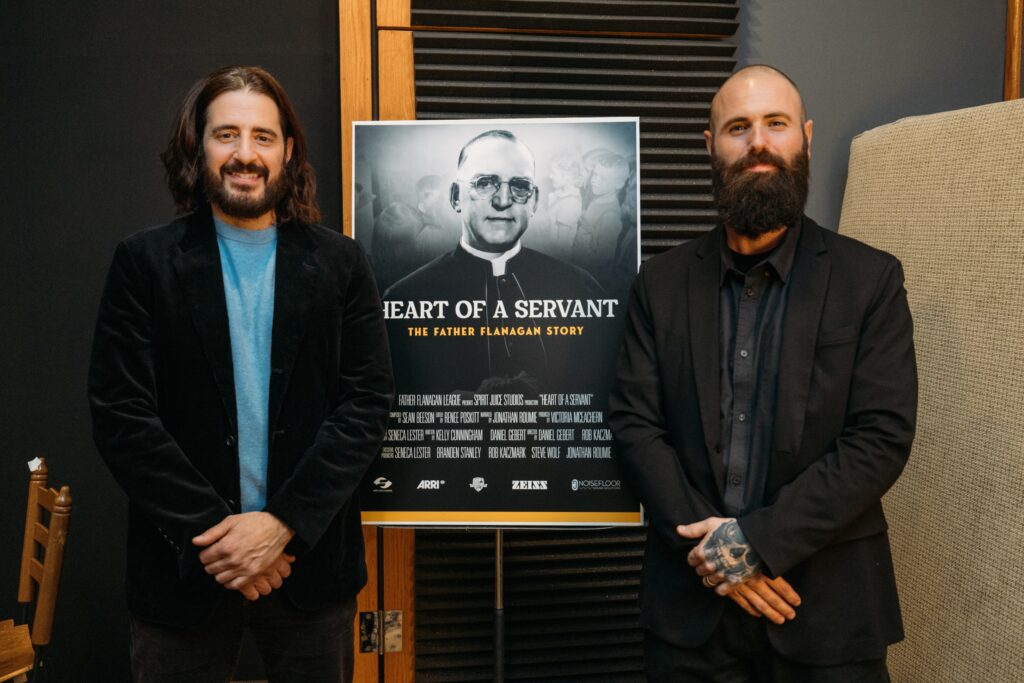 Rob and Jonathan stand in front of a movie poster
