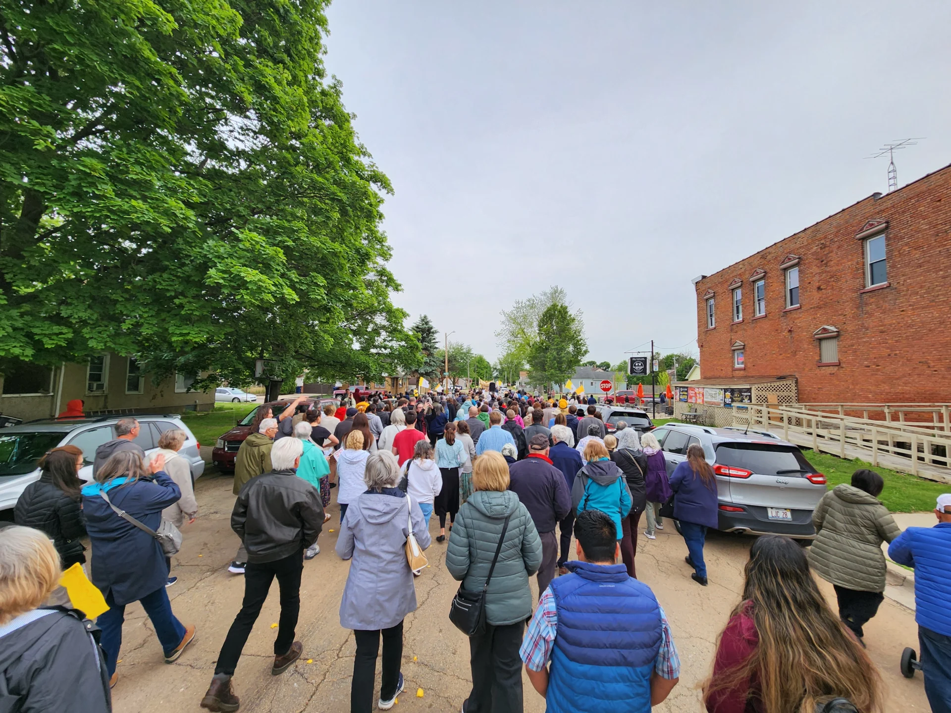 Pilgrims on the street moving forward while town buildings appear on the sides