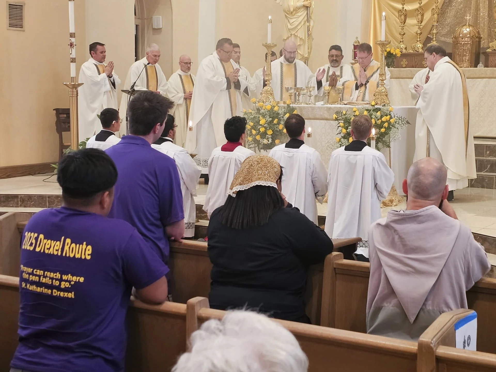 Priests pray during Mass while the faithful look on from the pews