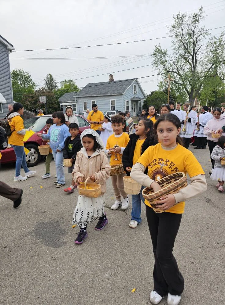 Girls wearing Corpus Christi tshirts throw flower petals at the start of the pilgrimage