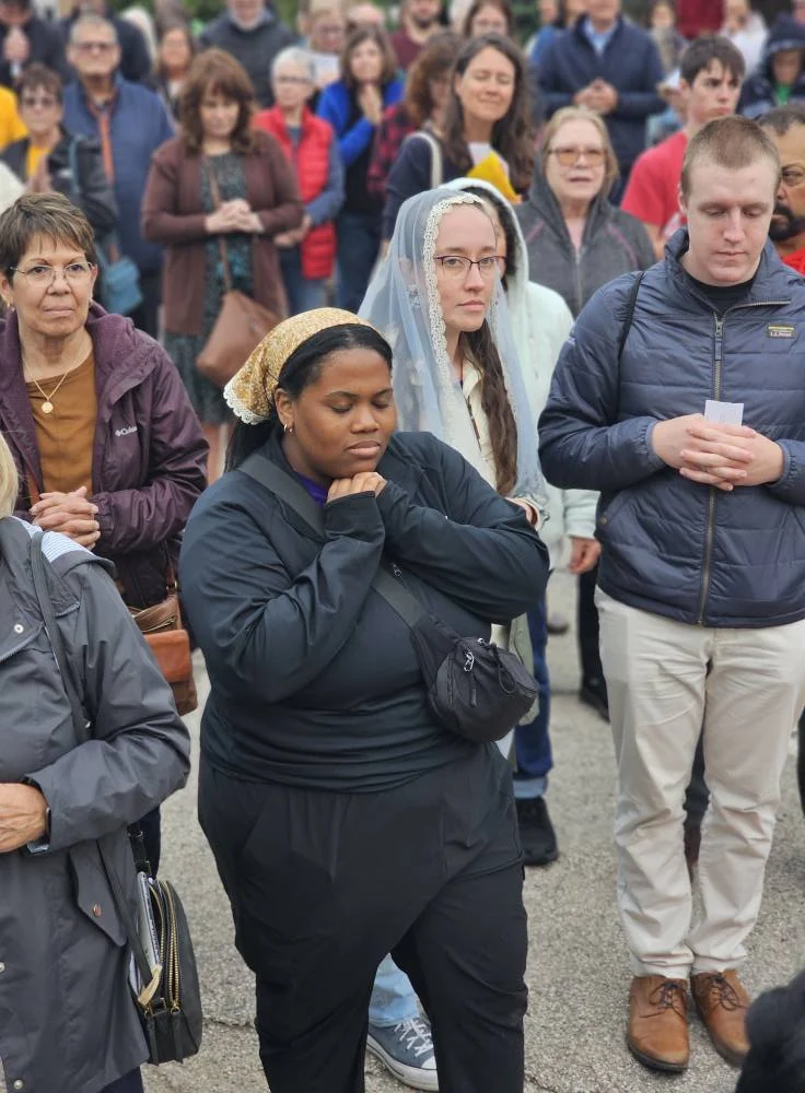 A woman prays silently while other people look on off frame