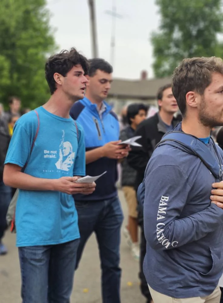Pilgrims walk forward praying.  One young man has a shirt on that reads "Be not afraid"