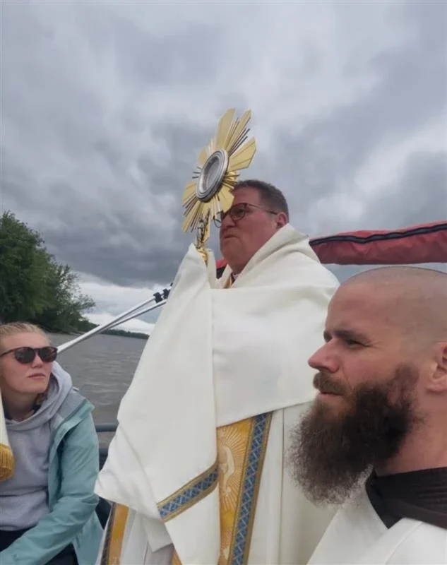 Father Michael Herlihey with Bishop Louis Tylka of Peoria, Illinois, and pilgrim Frances Webber cross the Mississippi River on May 21, 2025, in a fishing boat from the Diocese of Peoria into the Diocese of Davenport, Iowa, along the route of the 2025 Eucharistic Pilgrimage.