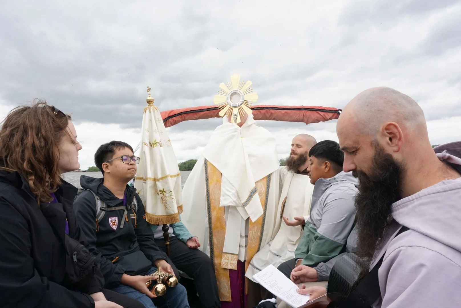 The Eucharist on a boat as pilgrims look on in prayer