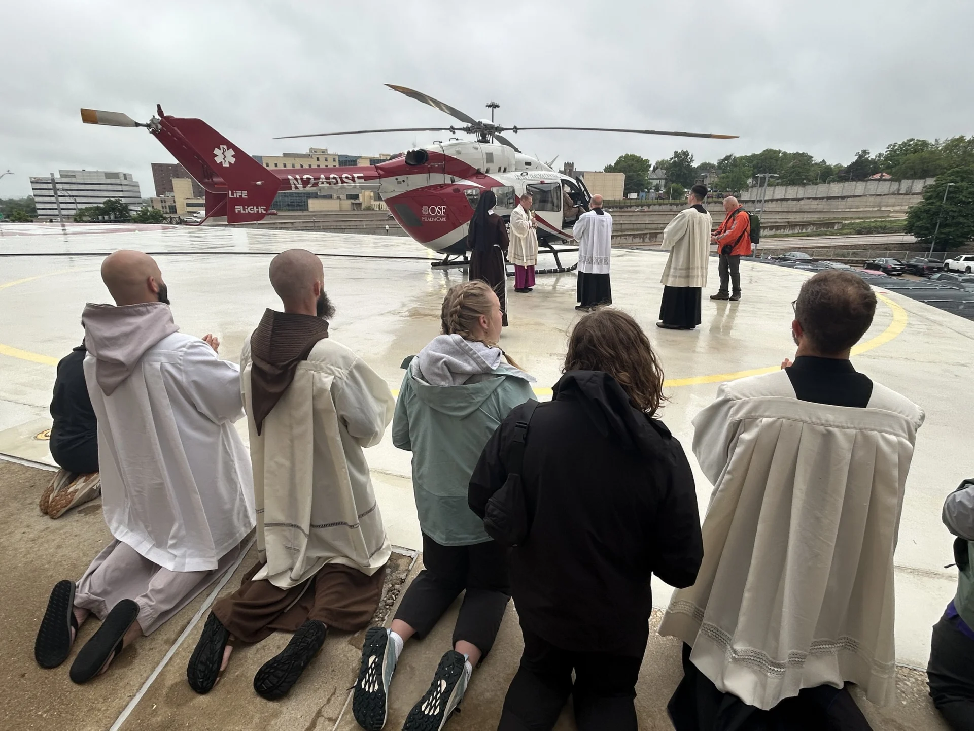 Faithful kneel as the Eucharist boards a helicopter