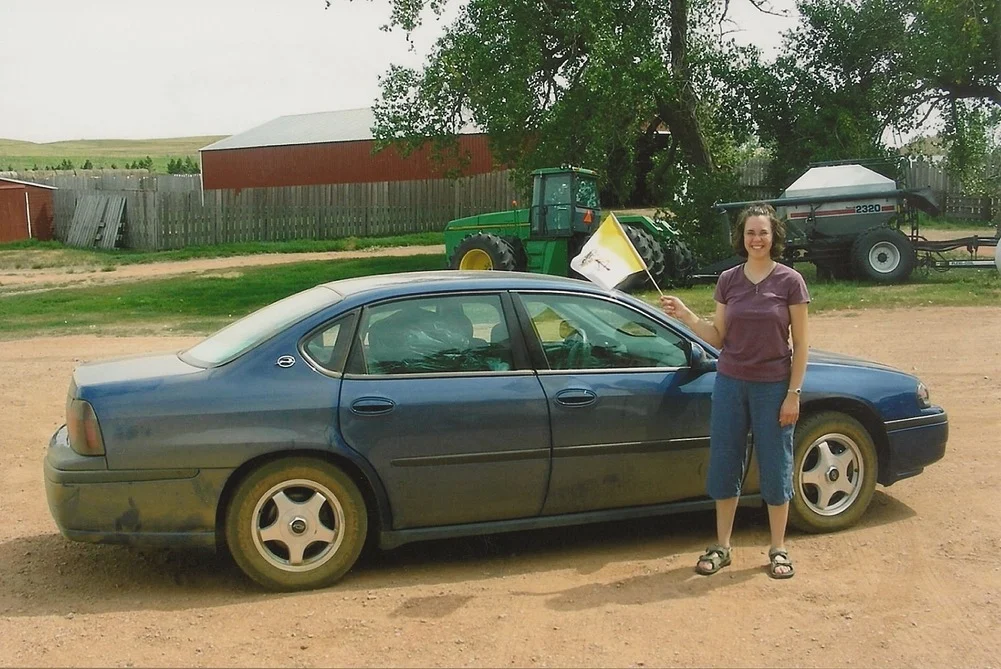 Michelle Duppong waves a vatican flag in front of a car